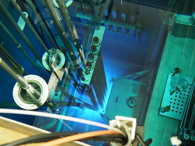 Looking down into NC State’s research reactor pool, with blue Cherenkov light glowing beneath the equipment.